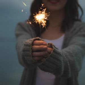 Woman holds sparkler, pondering what business is good for. Royal Commission asks, what's the purpose of business? Ethics in business.