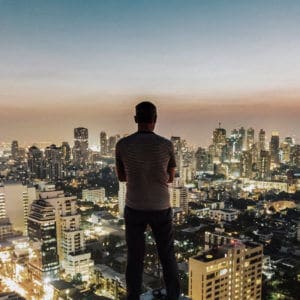 Ethics Explainer: Authenticity. Person overlooking a brightly lit cityscape at dusk, contemplating authenticity and ethical choices.