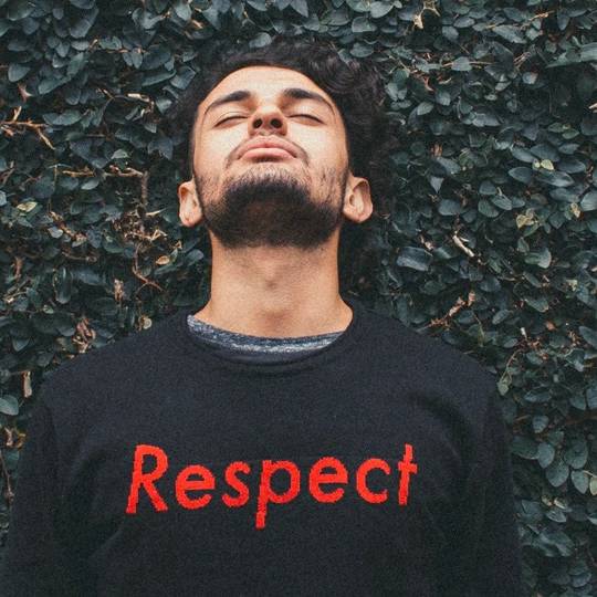 Person wearing Respect shirt, eyes closed, against leafy background. Respect for persons lost in legislation concept.