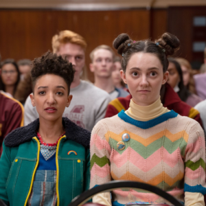 Sex Education TV show still. Two students in colorful outfits sit in an audience. TV shows about sex ed for sexual ethics.