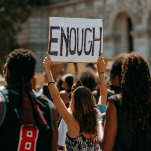 Crowd at a protest; woman holds sign saying ENOUGH. People believe in change, fighting for what they believe in at a demonstration.