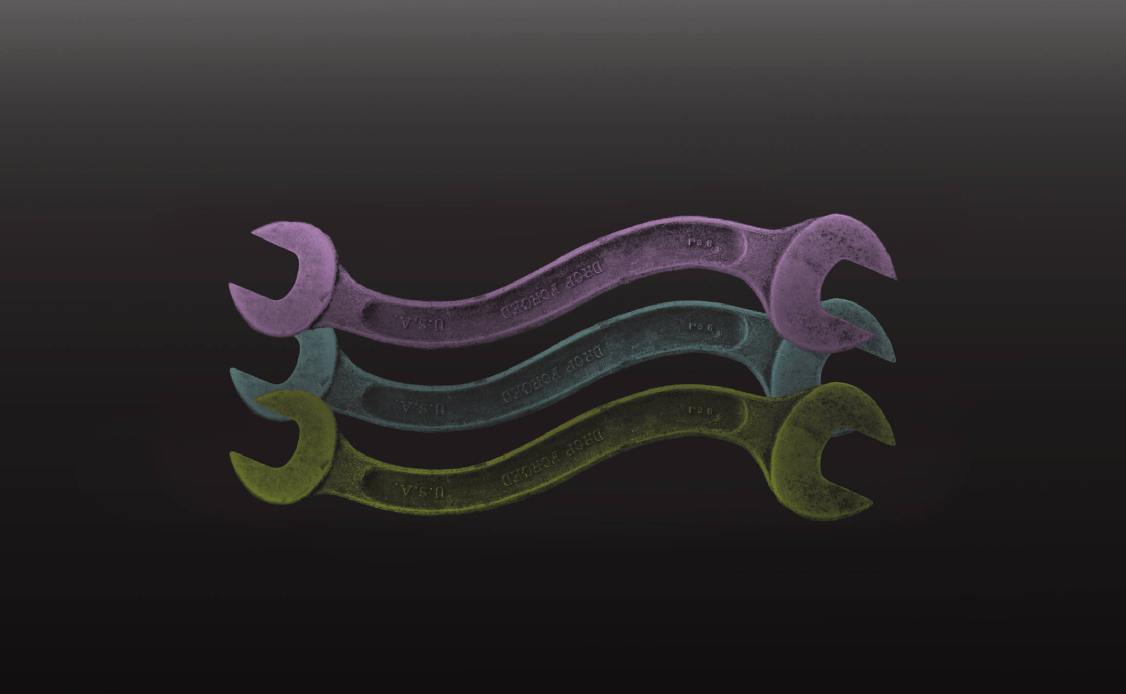Colorful wrenches stacked on a black background. Tools in purple, blue, and yellow. Drop forged USA wrenches. Industrial tool background.