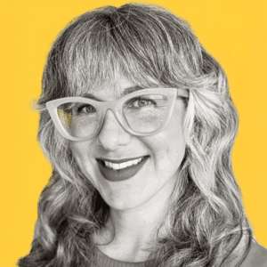Smiling woman with glasses, against a yellow background. The Ethics of Care concept image. Focus on compassion, empathy, and care in ethical considerations.