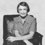 Ayn Rand, the famous novelist and philosopher, sits in a chair with a cigarette.