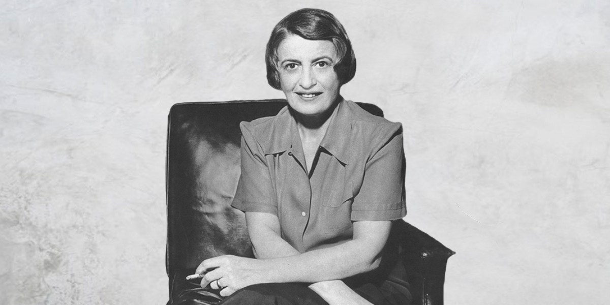 Ayn Rand, big thinker, in black and white, seated with a cigarette.