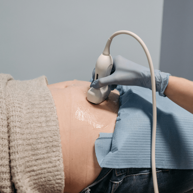 Pregnant woman getting an ultrasound. Doctor using ultrasound probe on patient's abdomen. Pregnancy healthcare.