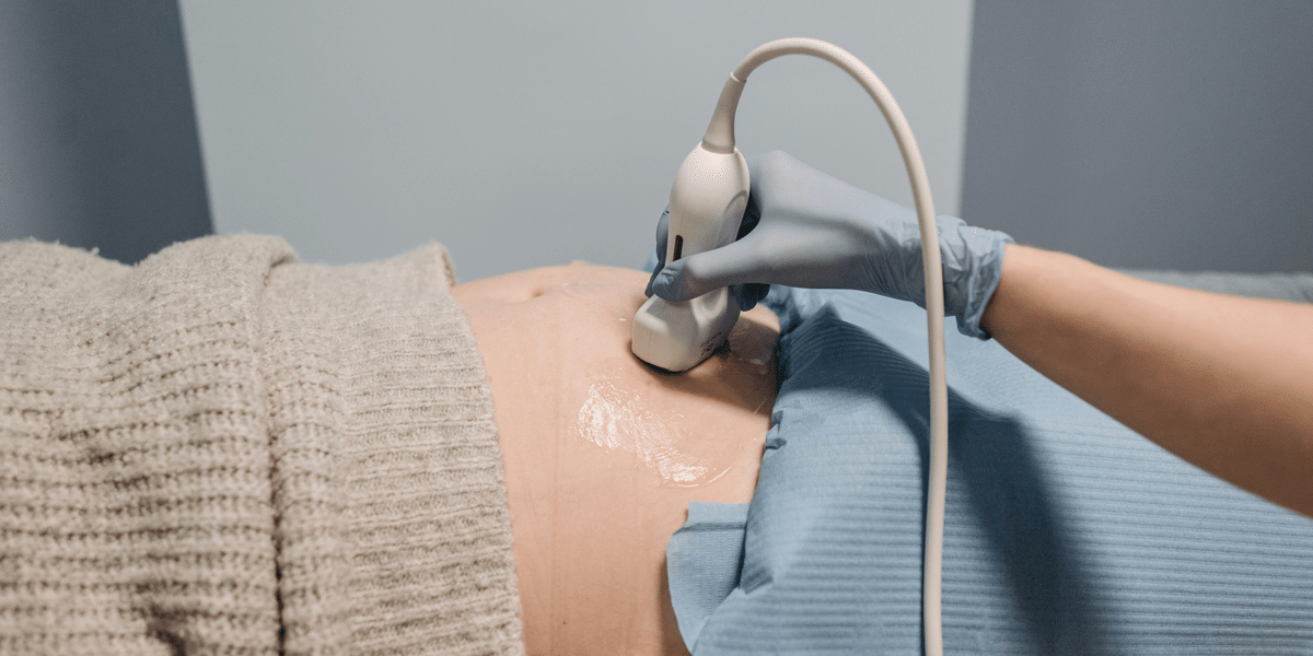 Pregnant woman getting ultrasound. Doctor using ultrasound probe on abdomen. Pregnancy pain management.