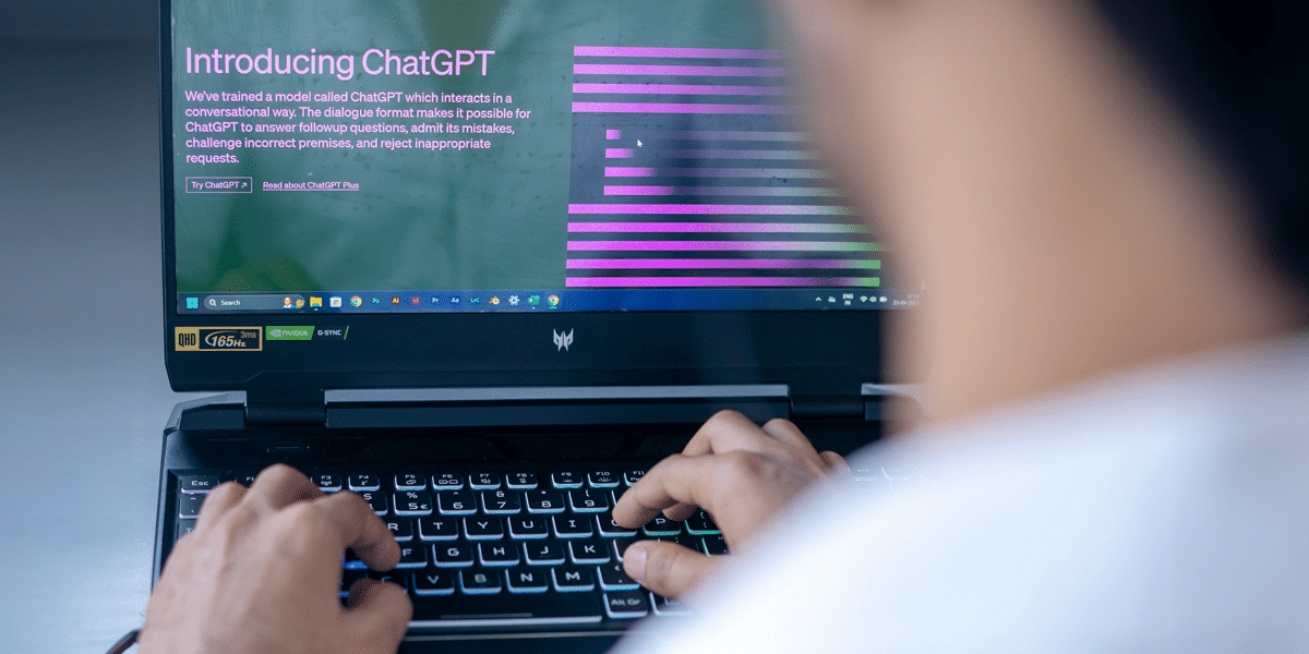 Typing on laptop using ChatGPT. AI ethics question: Should I use AI for work? Person using chatbot.