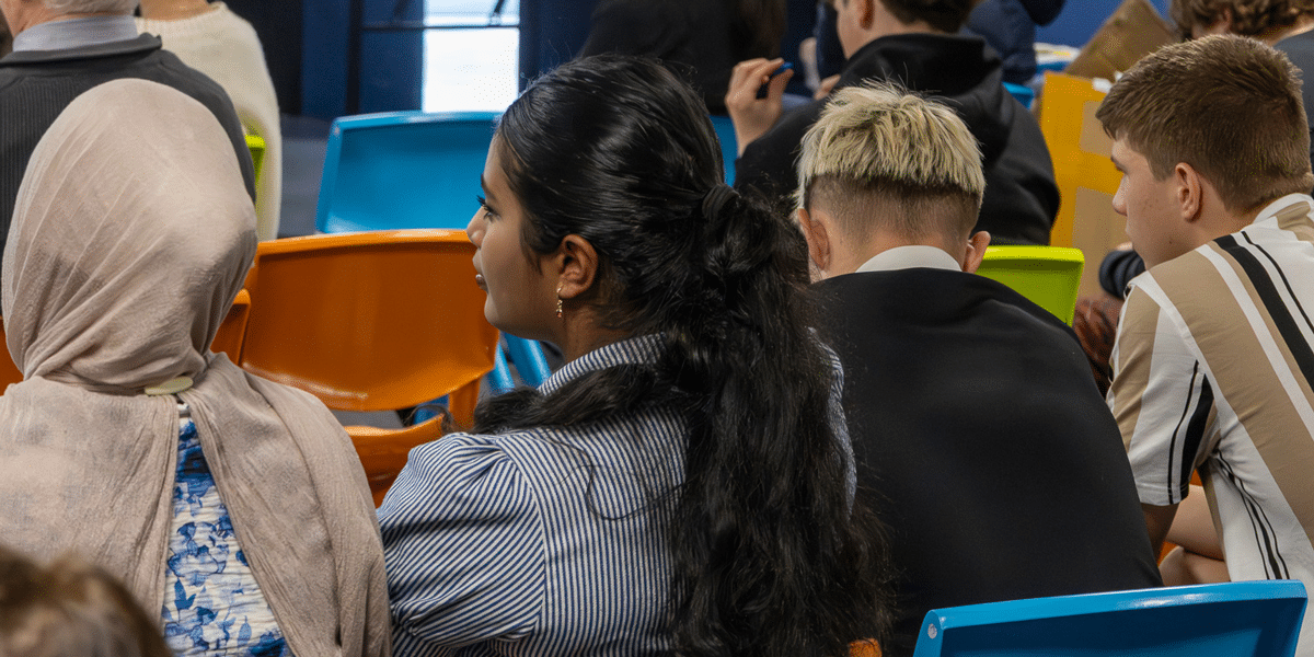 Diverse group attending a seminar about standing up against discrimination. Students listen attentively, promoting inclusivity.