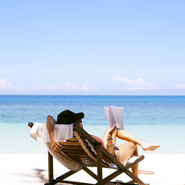 Woman reading on a beach chair. Leisure and a good life involve relaxation. Aristotle thought leisure was important for contemplation.
