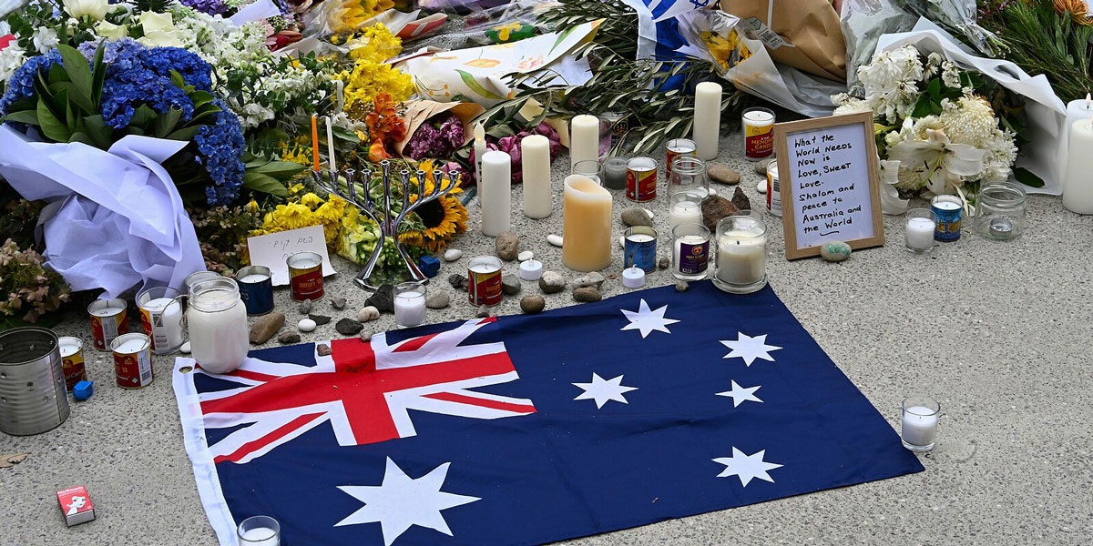 Memorial site for the Bondi massacre, a national response: Australian flag, candles, flowers, and heartfelt messages of love and peace.
