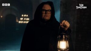 Alan Carr in The Traitors wearing a hooded cloak, holding a lantern. Is everyone secretly selfish, evil people on the show?