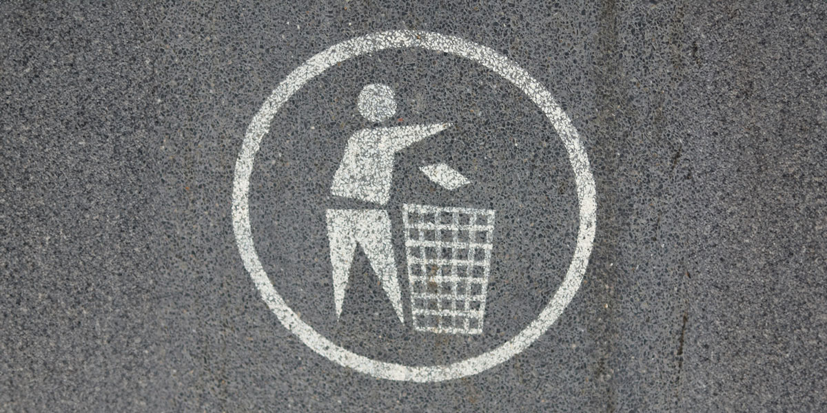 Boycotting symbol on asphalt: Person throwing trash into a bin, representing ethical consumerism and using your dollar as a voice for change.