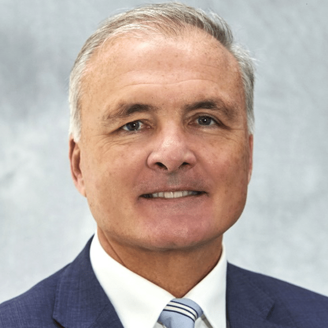 Headshot of a mature man in a suit and tie, discussing 'The Ethics of Surrender', likely a business professional or academic expert.