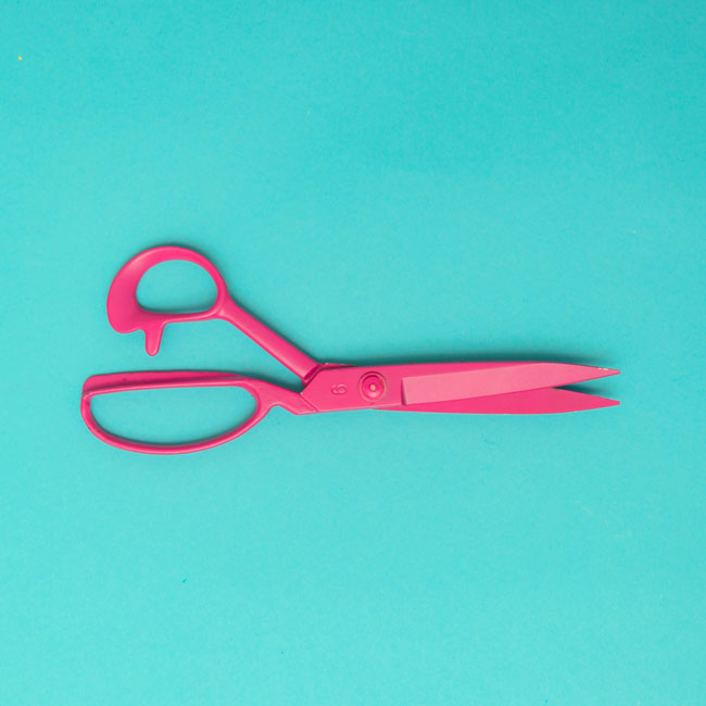 Pink surgical scissors symbolizing vasectomy decision at 30. Sharp tool on blue background, representing male sterilization and reproductive health choices.
