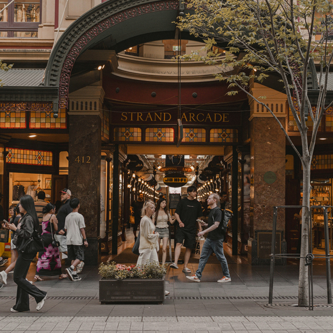 View of the Strand Arcade, an Australian shopping arcade, with shoppers entering. The ornate entrance has 'Strand Arcade' inscribed above it.