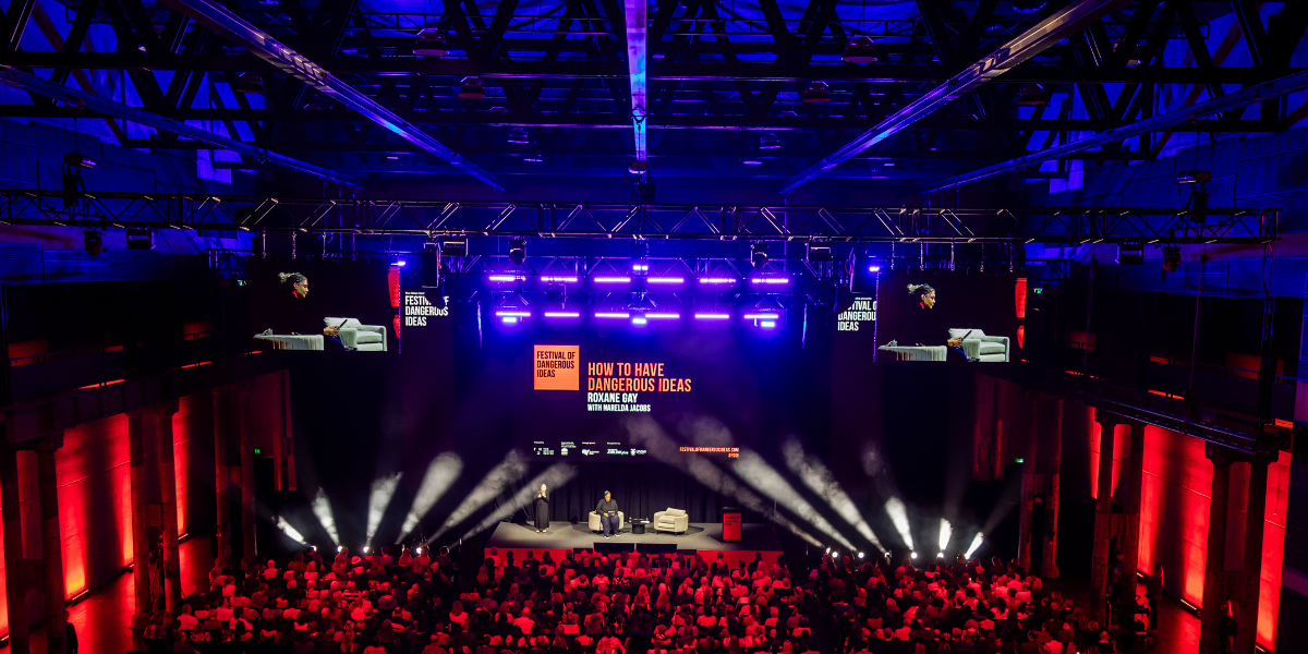 Stage at Festival of Dangerous Ideas featuring Roxane Gay with bright spotlights in a dark hall filled with an audience view