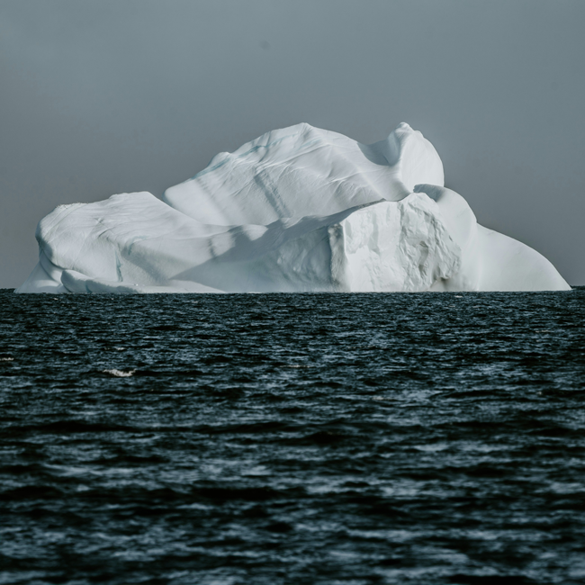 A large white iceberg floating in dark ocean waters representing dangerous ideas hidden beneath the surface of the sea