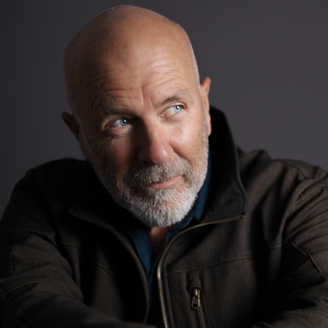 Richard Flanagan, author of Heresies, features in a thoughtful studio portrait with a shaved head and a grey trimmed beard