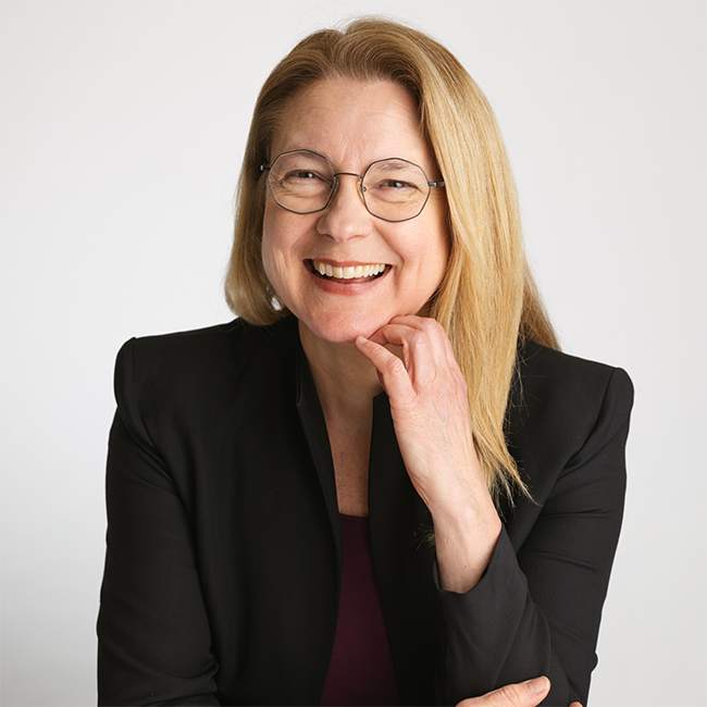 Smiling woman with glasses in a black blazer, representing ethics of intervention in a professional portrait setting
