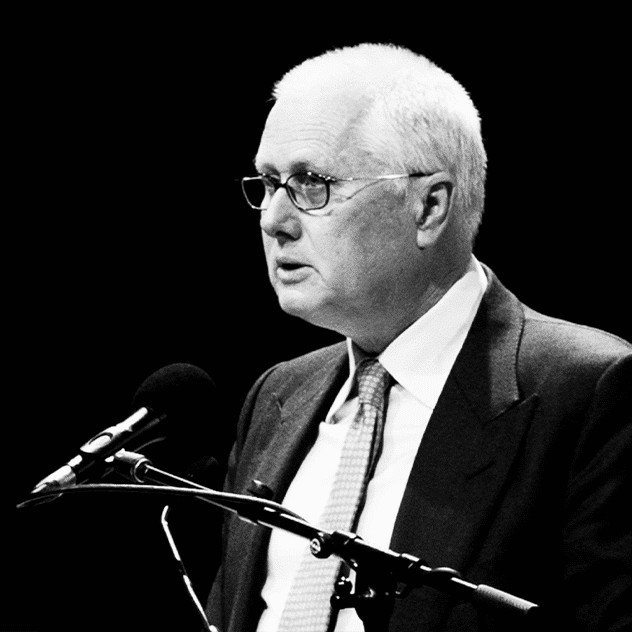Elderly man in suit speaks at microphones against black background, illustrating ethics in law and AI
